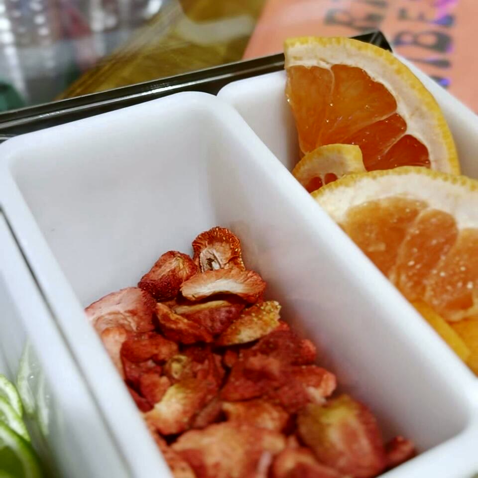 A garnish caddy of dried strawberries, grapefruit and lime at the bar