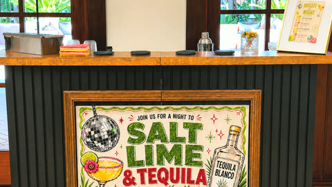 The Salt Rim mobile bar set up and ready at a client's venue, their custom framed &ldquo;Salt Lime & Tequila&rdquo; banner on the front and the printed drink menu standing on the bar top