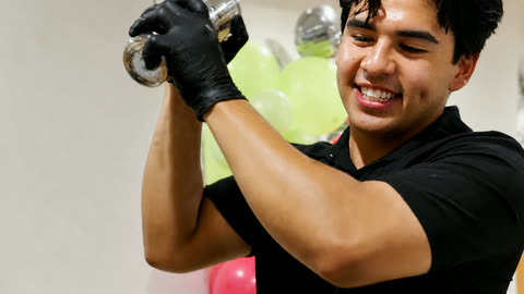 A Salt Rim bartender shaking a cocktail in a tin, smiling, at a client's event