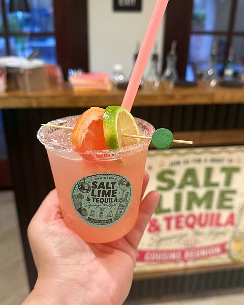 A finished cocktail with a salted rim, grapefruit and lime, held up in a cup carrying the event&rsquo;s own 2-inch &lsquo;Salt Lime & Tequila&rsquo; sticker