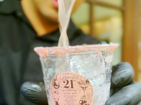 A drink being poured into an ice-filled cup with a custom birthday sticker